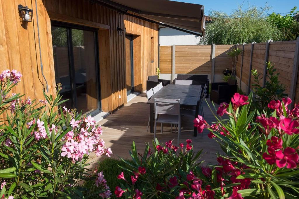 een patio met een tafel, stoelen en bloemen bij Maison Bassin d'Arcachon - Arès - Proche plage et commerces, 3 chambres, 8 personnes, Climatisation in Arès