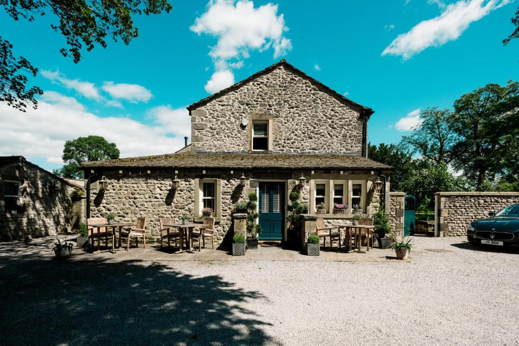 un edificio de piedra con mesas y sillas y un coche en The Rectory Rooms, Studio 1, en Skipton