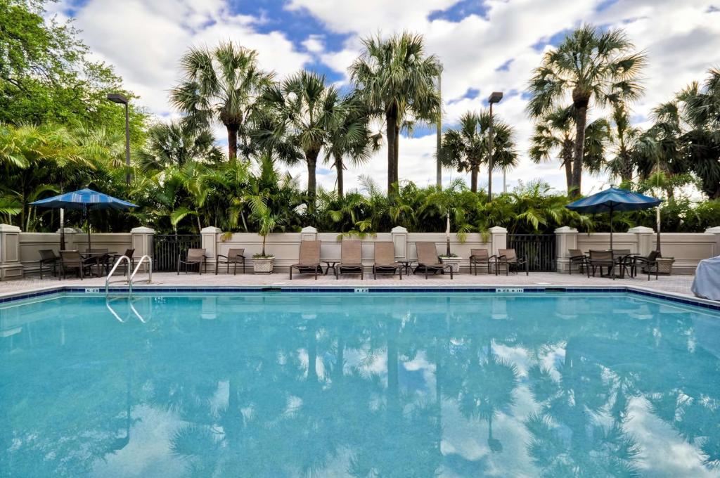 une grande piscine avec des chaises et des palmiers dans l'établissement Hyatt Place Tampa Airport/Westshore, à Tampa