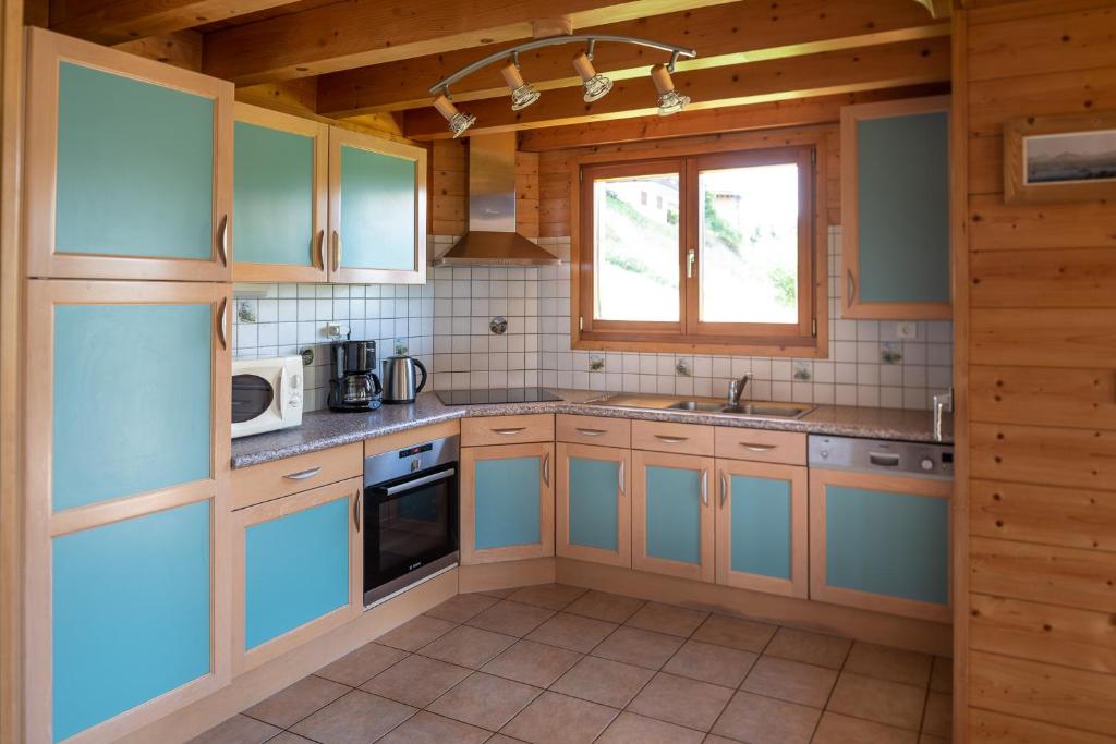 a large kitchen with blue cabinets and a window at Chalet Le Lapye in Les Gets