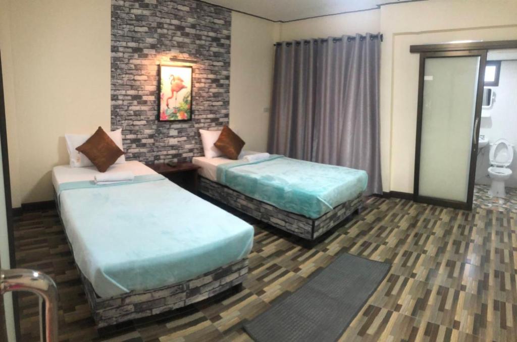a hotel room with two beds and a window at Khao Luang Resort in Lan Saka