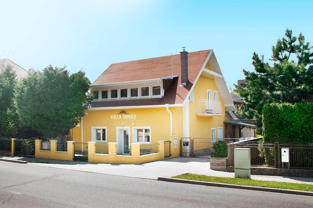 ein gelbes Haus mit einem Zaun davor in der Unterkunft Villa Sipeky in Senec