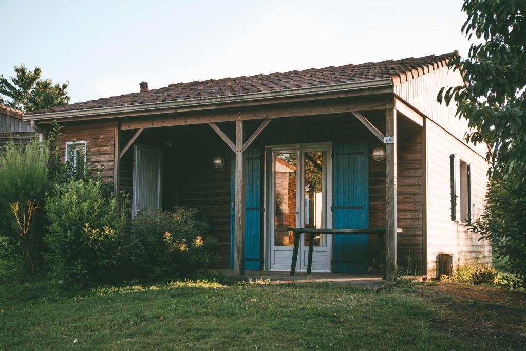 una pequeña casa con una puerta delantera azul en Terres de France - Natura Resort Pescalis, en Moncoutant