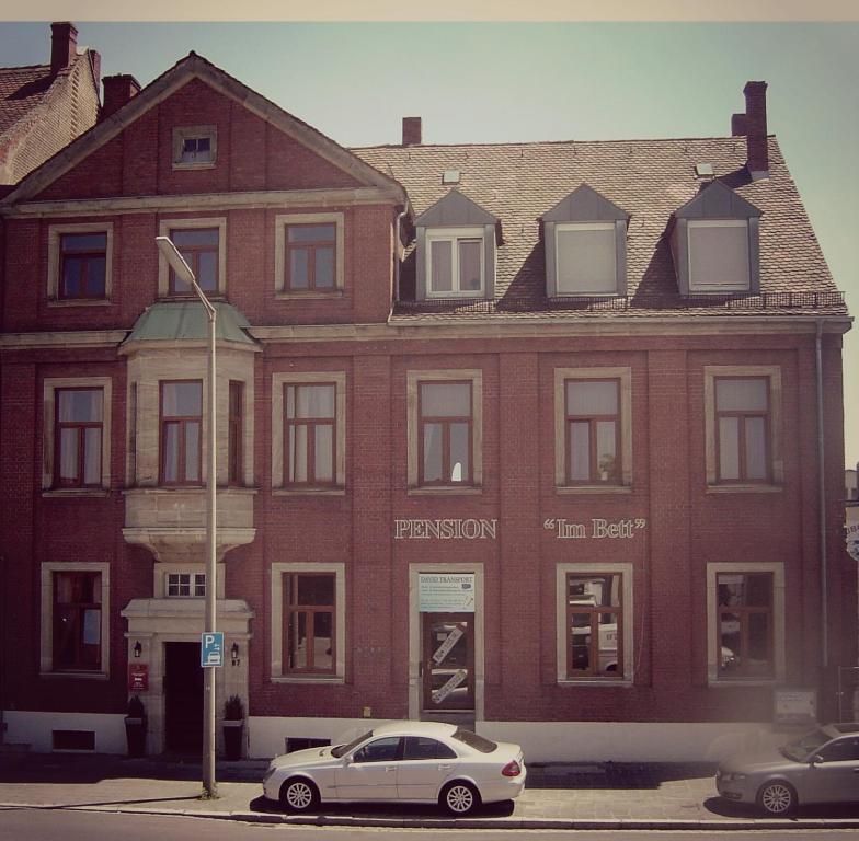 a white car parked in front of a red brick building at Pension Im Bett in Nuremberg