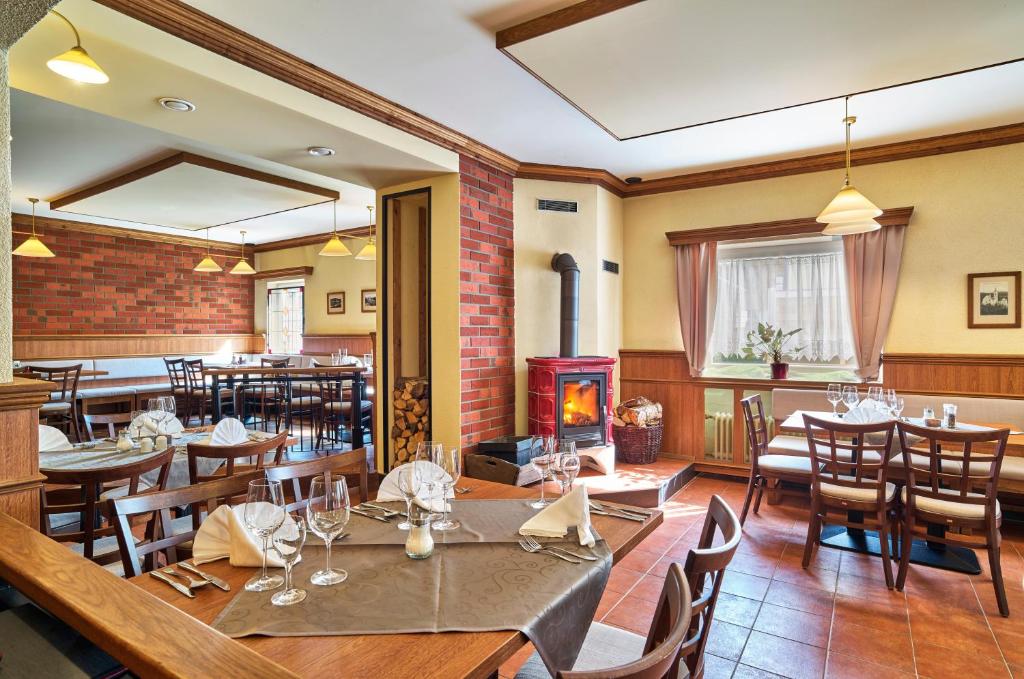 ein Restaurant mit Tischen und Stühlen und einem Kamin in der Unterkunft Hotel Eisensteiner Hof in Bayerisch Eisenstein