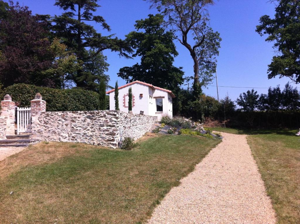 ein Steinzaun und ein kleines Haus in einem Hof in der Unterkunft Domaine du Chêne Crucy in Liré
