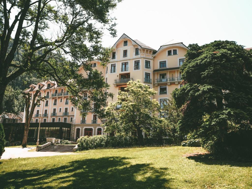 un grand bâtiment avec une pelouse devant lui dans l'établissement Terres de France - Appart'Hotel le Splendid, à Allevard