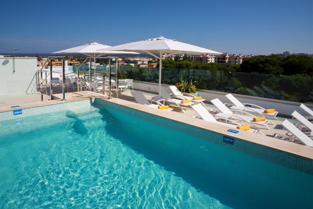a swimming pool with chairs and umbrellas at Hotel Seasun Aniram in Playa de Palma