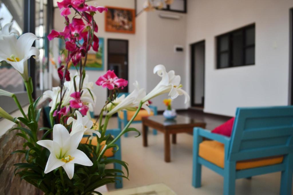 una sala de estar con flores rosas y blancas y una silla azul en CASA LUYA URCO, en Chachapoyas