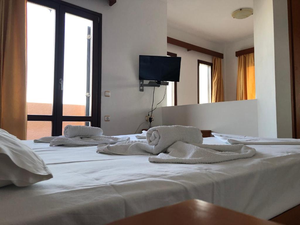 un grupo de tres camas blancas con toallas. en Kyma Hotel, en Marathokampos