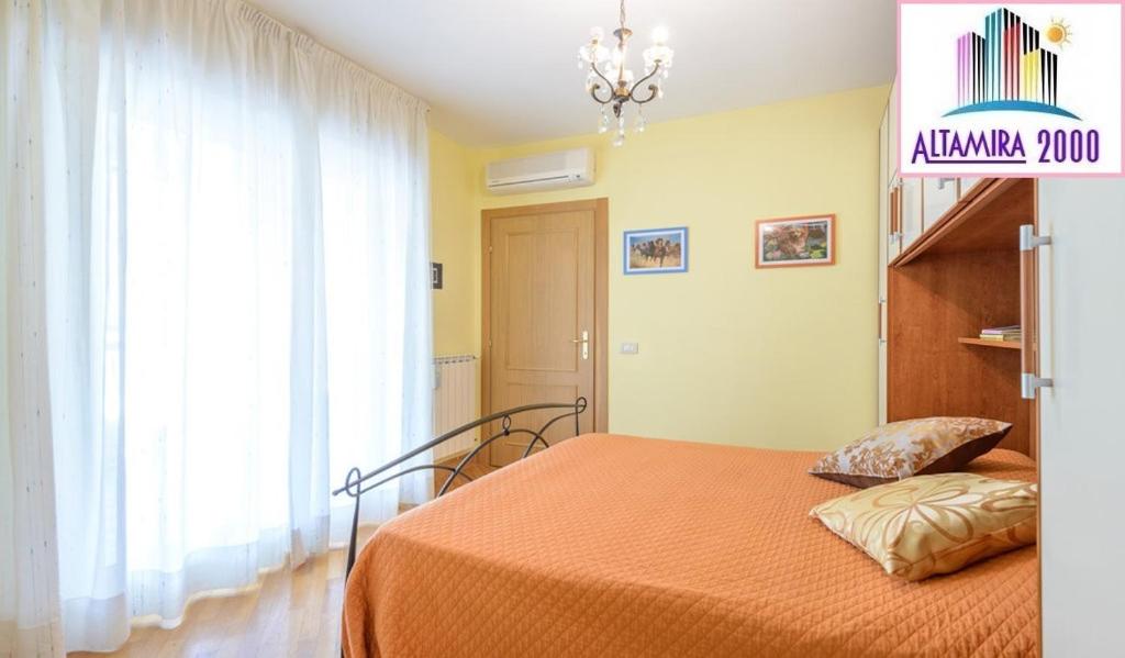 a bedroom with a bed with an orange blanket and a window at Altamira 2000 by GABRIELLA in Rome