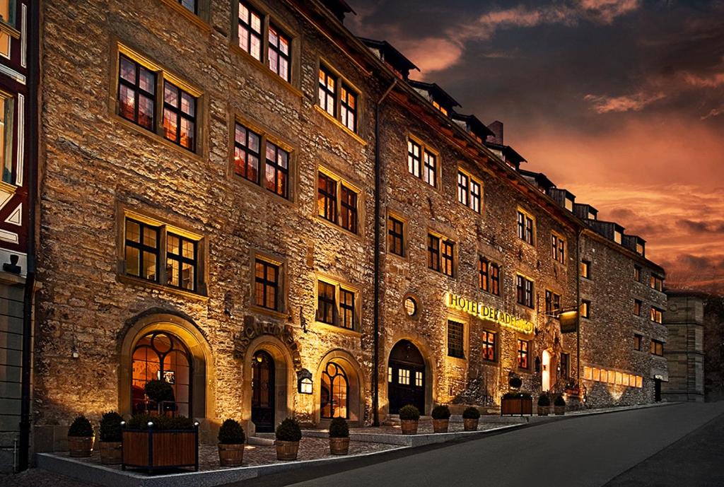 a large brick building with a sunset in the background at Trip Inn Hotel Der Adelshof in Schwäbisch Hall