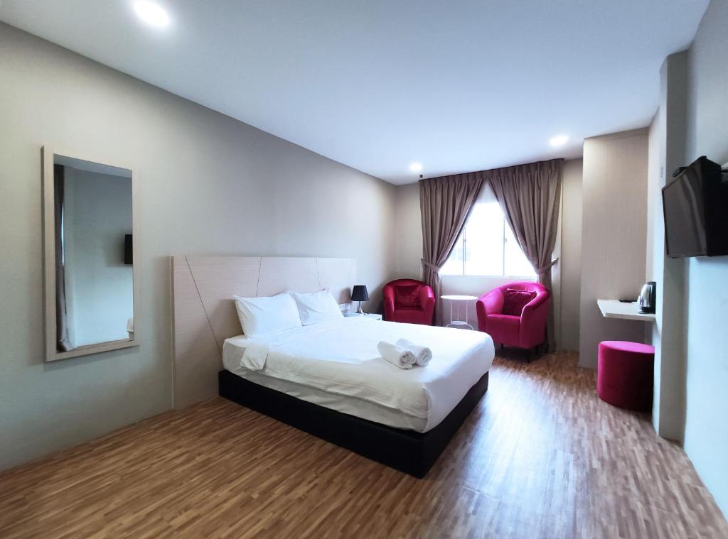 um quarto de hotel com uma cama e duas cadeiras vermelhas em Princess Hotel Pontian em Pontian Kechil