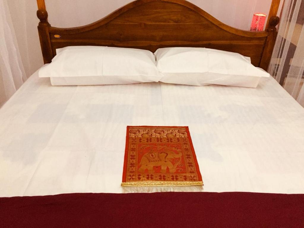 Bett mit einem Kopfteil aus Holz und einem Teppich darauf in der Unterkunft New Toropi Homestay in Gadaladeniya