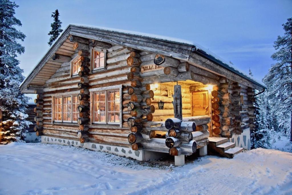 eine Blockhütte im Wald im Schnee in der Unterkunft VILLA KELO in Ruka