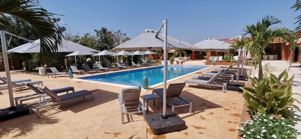 a swimming pool with lounge chairs and umbrellas at La Taniere Villa Metsu in Saly Portudal
