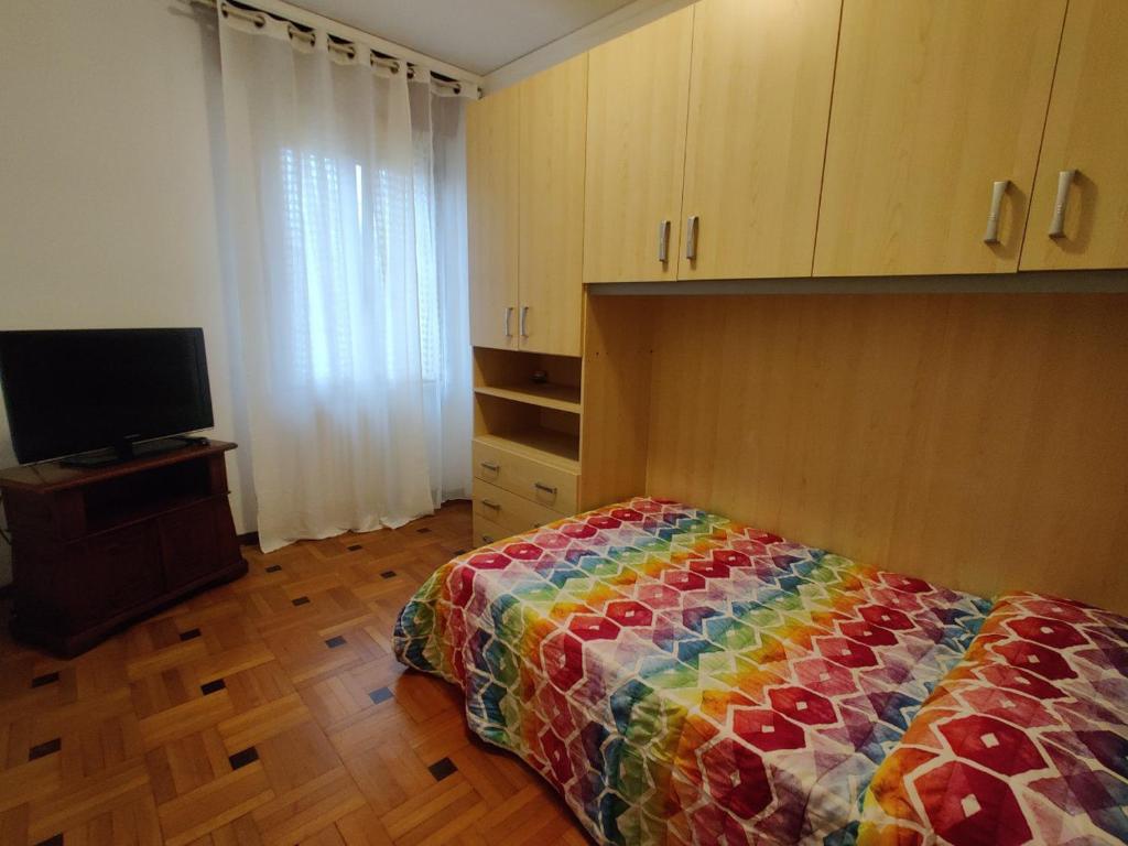 1 dormitorio con 1 cama colorida y TV en Tranquillità e cordialità a 30 minuti da MIlano, en Busto Arsizio