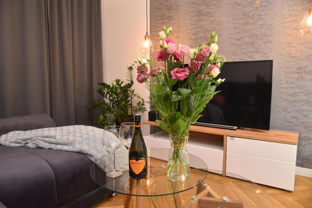 a bottle of wine and a vase of flowers on a table at Good Feeling Rynek Wrocław in Wrocław