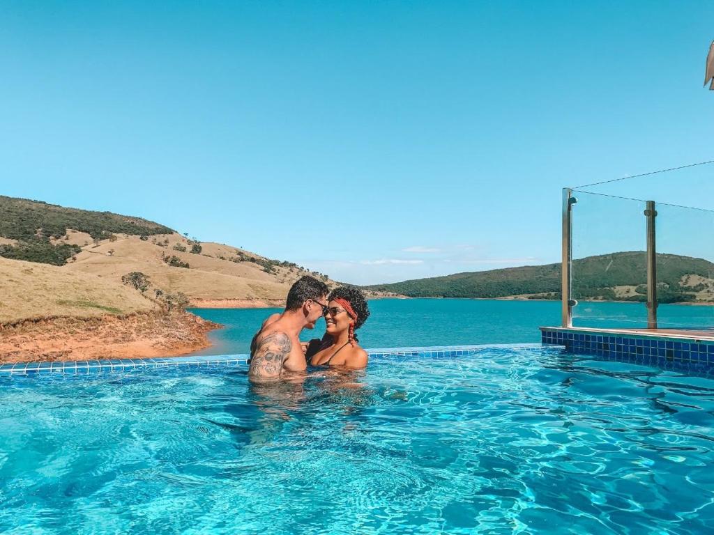 dos personas en una piscina en el agua en Hotel Boutique Coração Aberto, en Capitólio