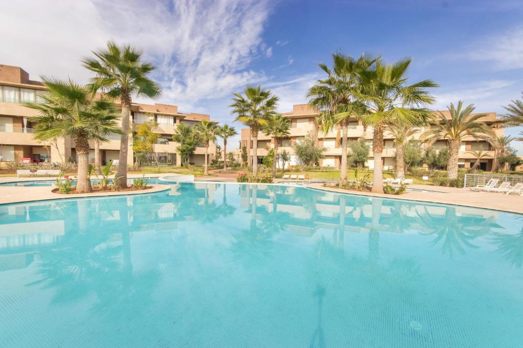 a large swimming pool with palm trees and buildings at Vue époustouflante sur L Atlas - Prestigia in Marrakesh