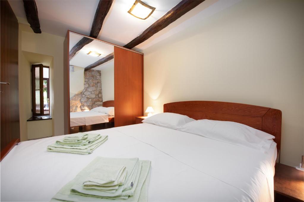 sypialnia z białym łóżkiem z lustrem w obiekcie 2 Apartments in Old Stone House near Opatija w mieście Ičići