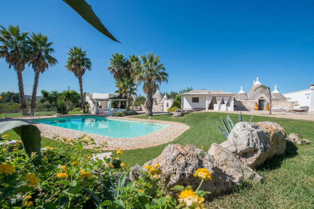 a backyard with a swimming pool and a house at HelloApulia - Trulli Oleandro in Ostuni