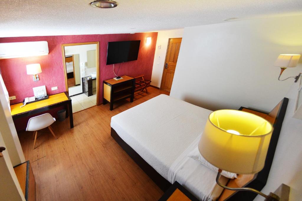 Dormitorio con cama, escritorio y TV en Centro 19 Hotel en Querétaro