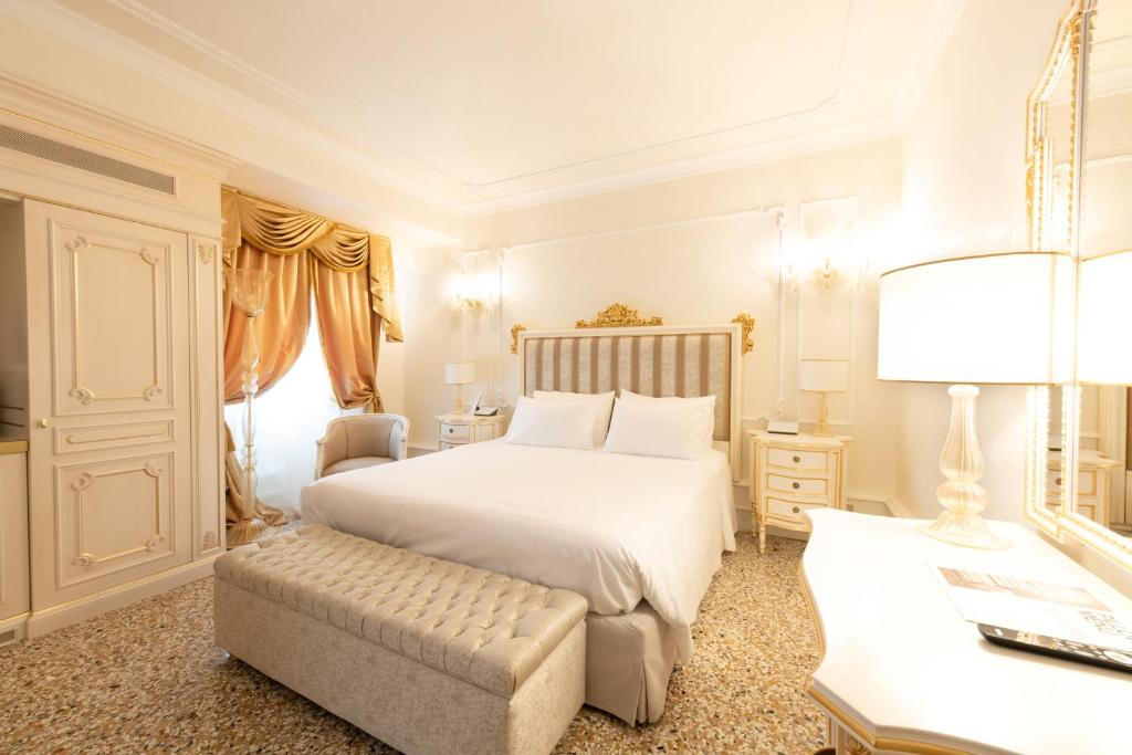 a bedroom with a large white bed and a chair at Ca' Bonfadini Historic Experience in Venice