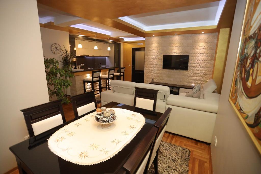 un soggiorno con tavolo, sedie e divano di Zlatar LUX Apartman a Nova Varoš