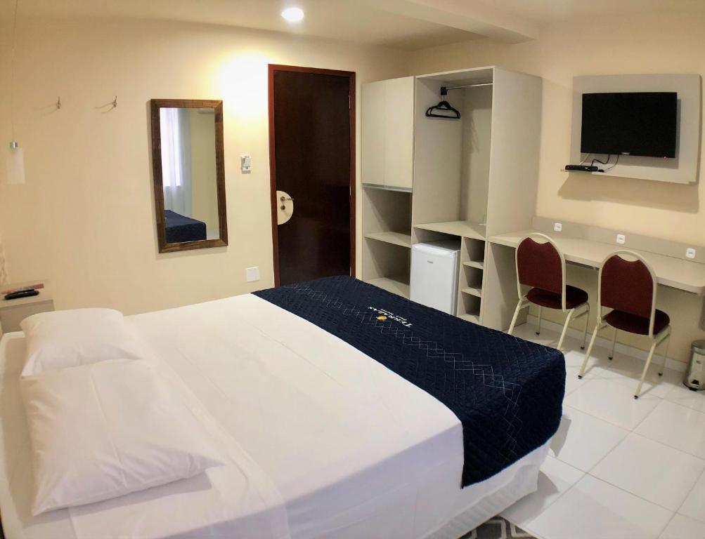 Schlafzimmer mit einem Bett, einem Schreibtisch und einem TV in der Unterkunft Terrazas Hotel in Curitiba