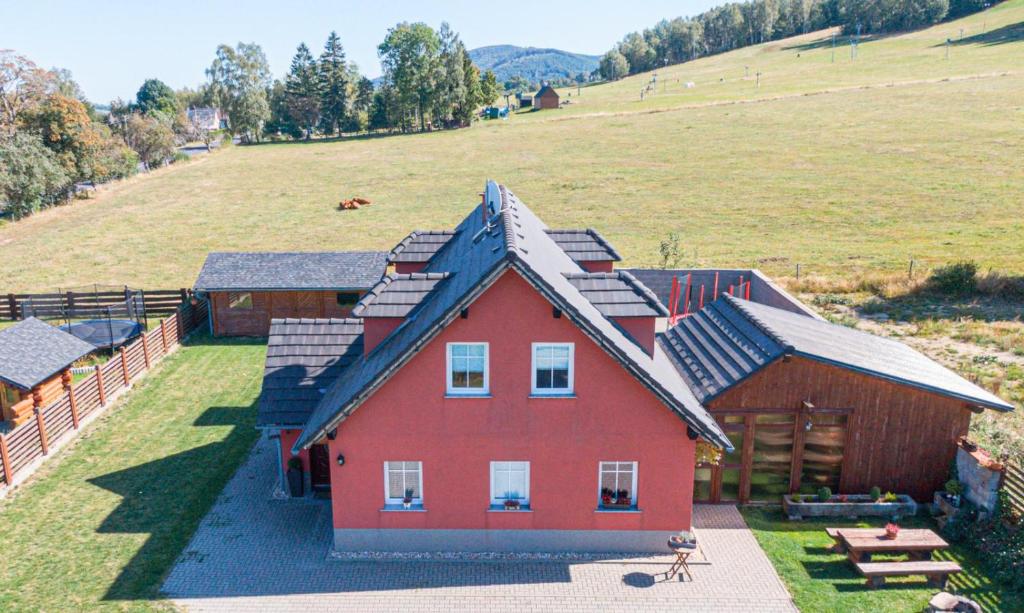 Horní PodlužíにあるChalupa u vleku Horní Podlužíの田地の横の丘の上の赤い家
