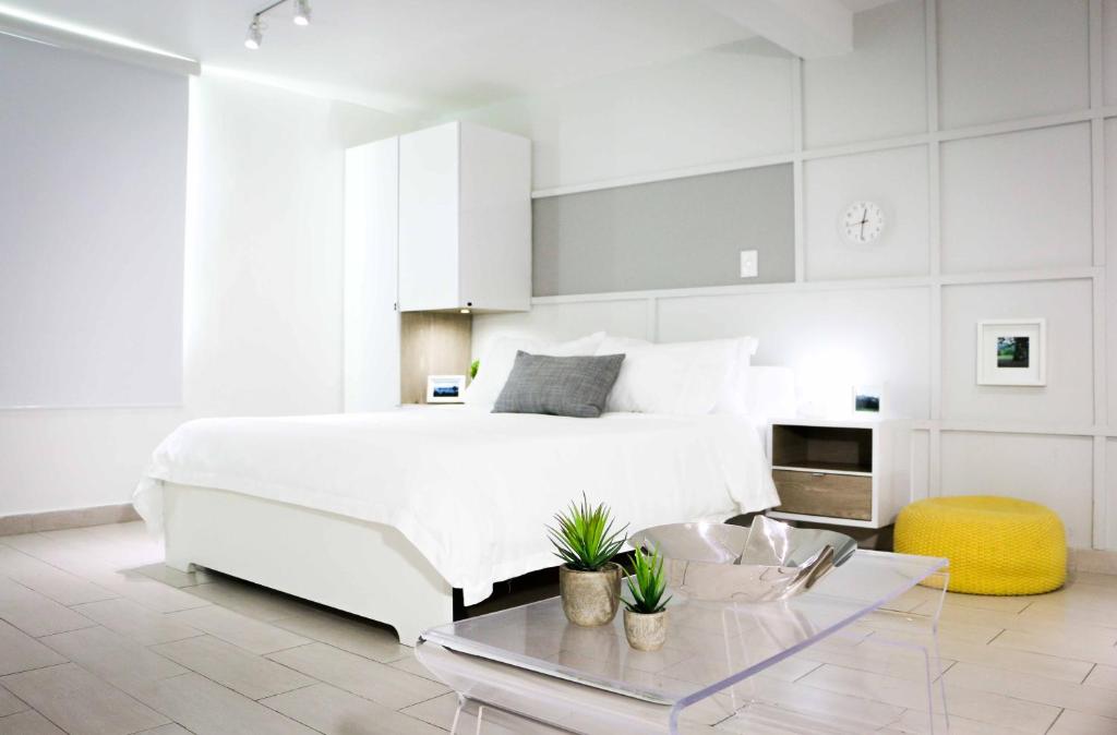 a white bedroom with a white bed and a table at Avila Guesthouse in San Juan