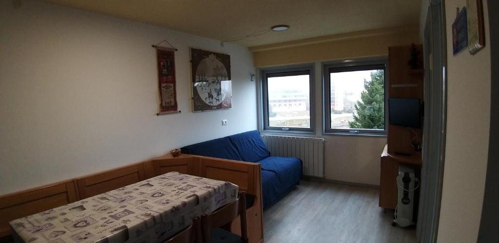 Cette chambre comprend un lit, un canapé bleu et une fenêtre. dans l'établissement BILOCALE N.10, à Passo del Tonale
