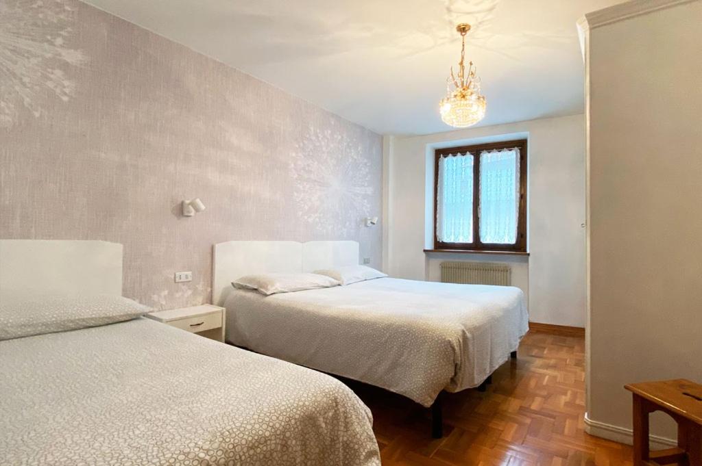 モルヴェーノにあるAppartamento Zeni - Dolomiti di Brentaのベッドルーム1室(ベッド2台、シャンデリア付)