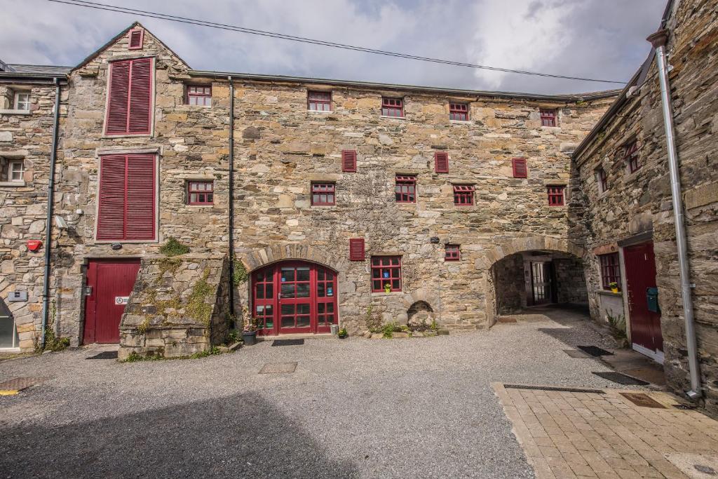 ein altes Steingebäude mit roten Türen und Fenstern in der Unterkunft Old Mill Holiday Hostel in Westport