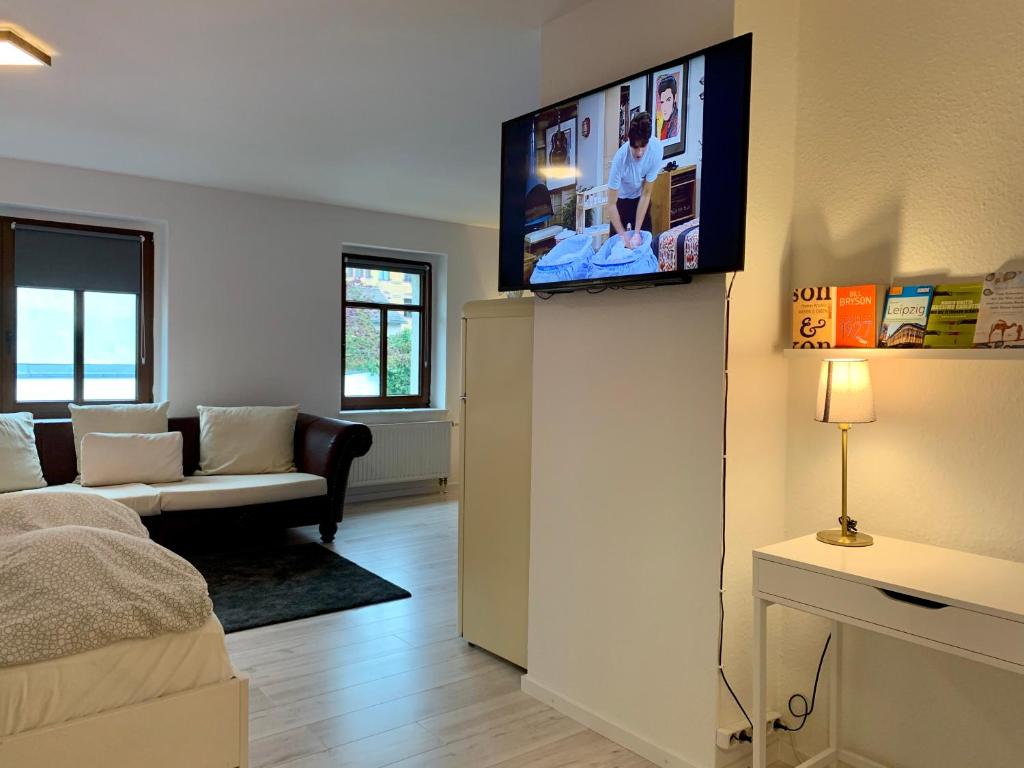 uma sala de estar com televisão na parede em Hinterhaus Apartment No3 em Leipzig