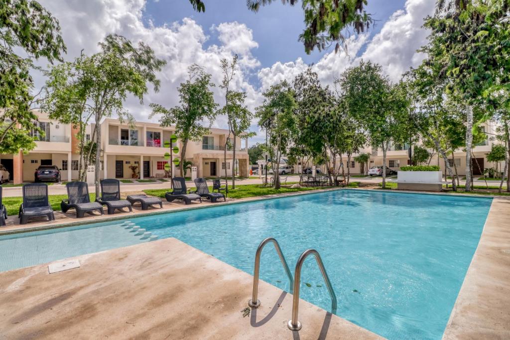 een zwembad met stoelen en bomen voor een gebouw bij Selvanova Coto 4B, Villa Flamingos 437F in Playa del Carmen