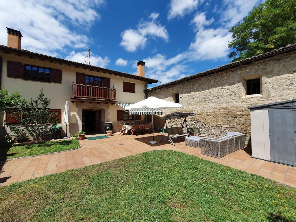 een patio met een parasol en een gebouw bij Casa familiar con jardín “Arana Etxea” EBI01207 in Orduña