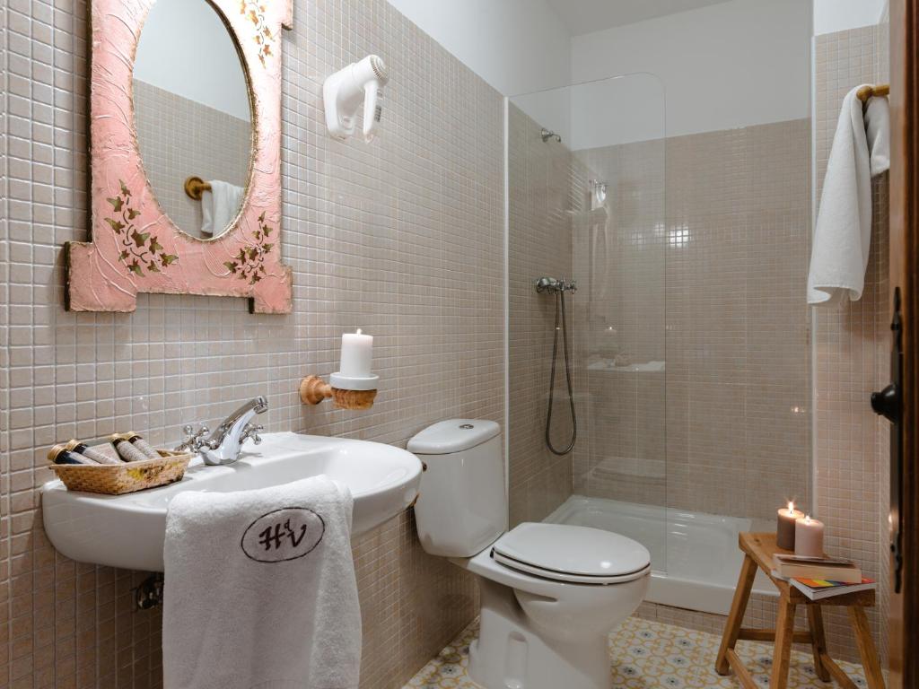 Un baño con lavabo, inodoro y espejo. en Hospedería del Valle Boutique Apartments, en Gargantilla del Lozoya