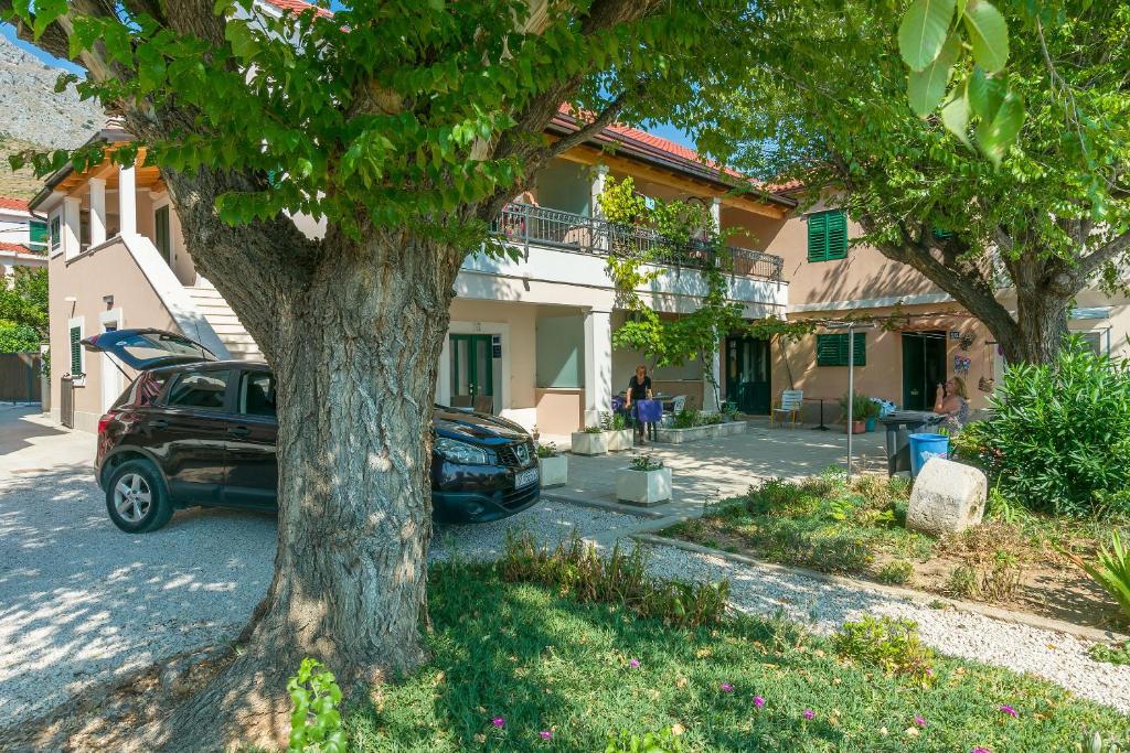 un coche aparcado frente a una casa con un árbol en Apartments Roko, en Duće