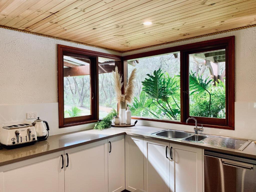 cocina con fregadero y 2 ventanas en William Bay Cottages, en Denmark