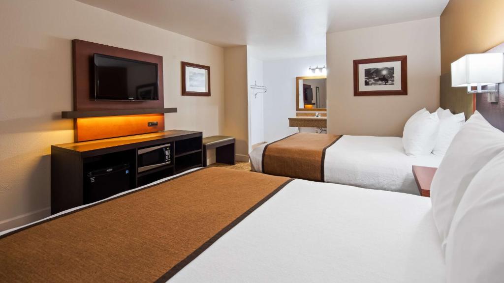 a hotel room with two beds and a flat screen tv at Best Western Discovery Inn in Tucumcari