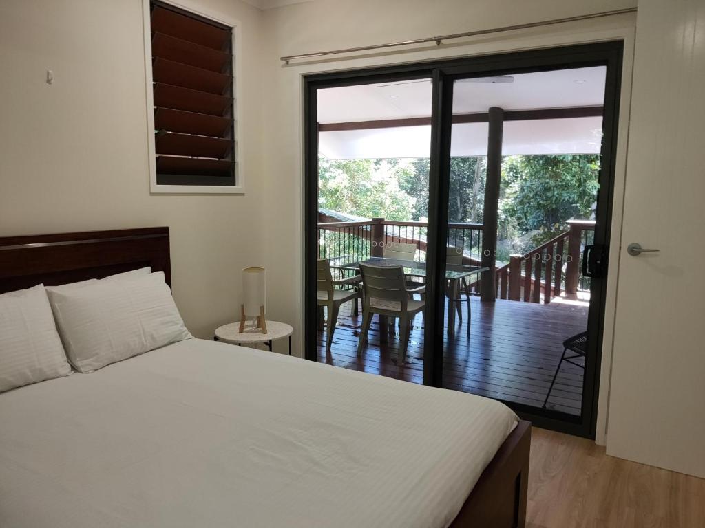 a bedroom with a bed and a balcony with a table at Rainforest Retreat in Mission Beach