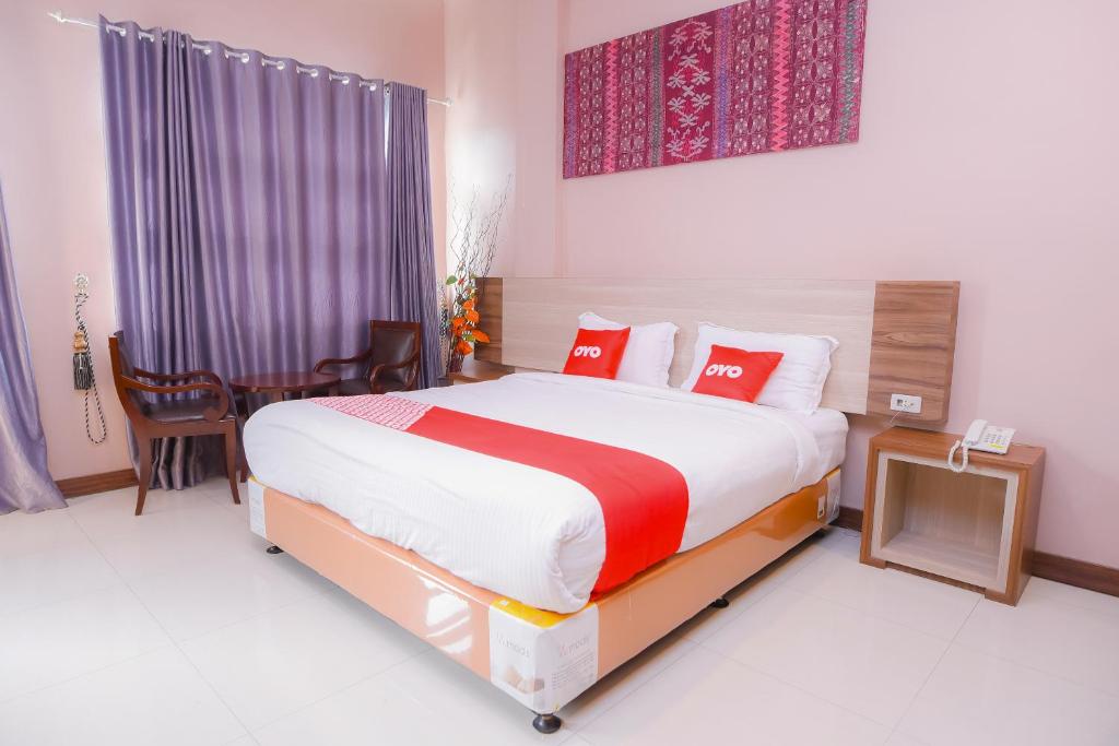 a bedroom with a large bed with red pillows at Super OYO Capital O 1630 Hotel Syariah Ring Road in Banda Aceh