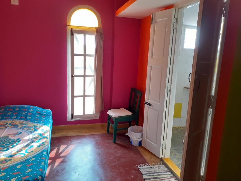 een kamer met een bed, een raam en een stoel bij Holi-Wood Guesthouse in Pondicherry