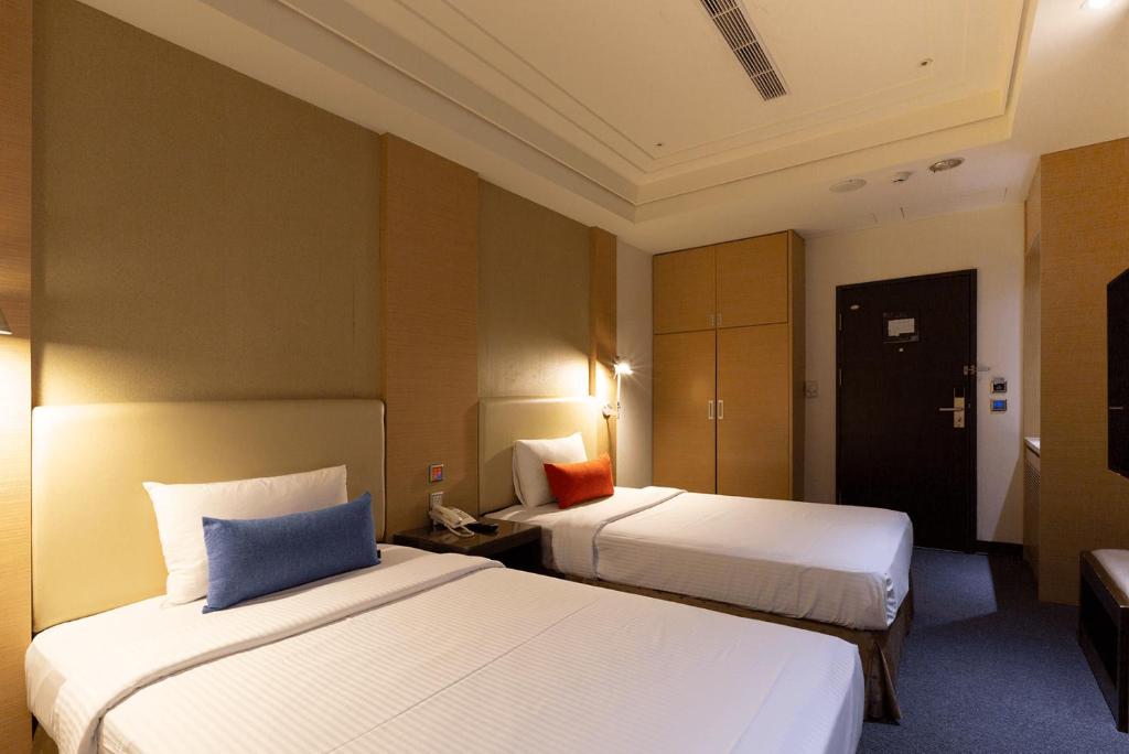 a hotel room with two beds and a door at Ever Delightful Business Hotel in Chiayi City