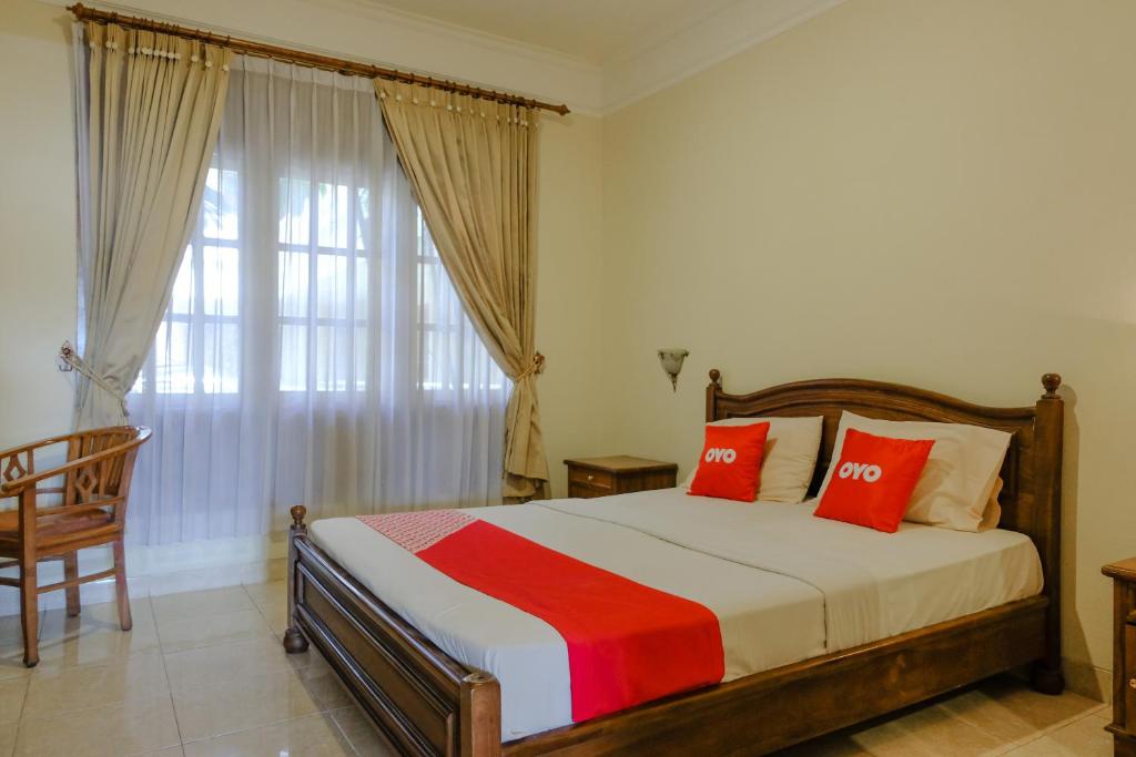 Super OYO 1803 Hotel Sarangan Permai في ماديون: غرفة نوم بسرير ومخدات حمراء ونافذة