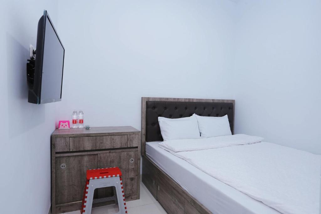 una camera con letto e sgabello rosso di ratana cengkareng syariah a Giacarta