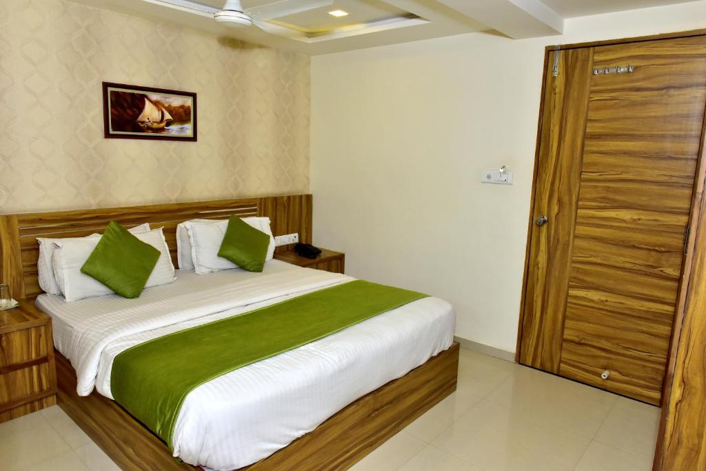 um quarto com uma cama grande e almofadas verdes e brancas em Hotel Shobhna Palace em Ahmedabad