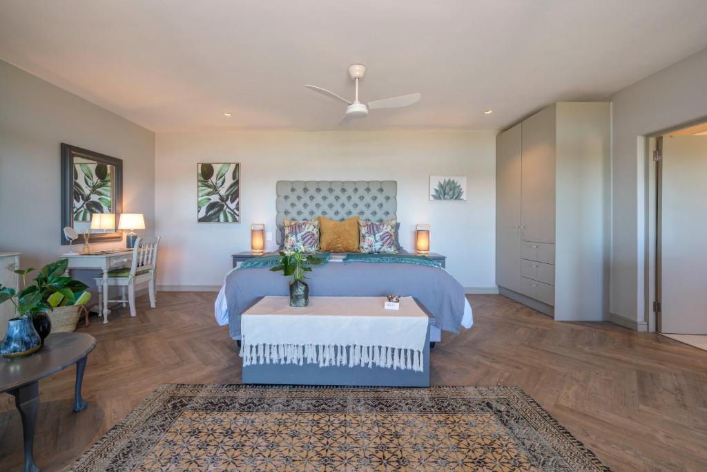 a bedroom with a blue bed and a table at 365 Sunset Self Catering Apartments in Noordhoek